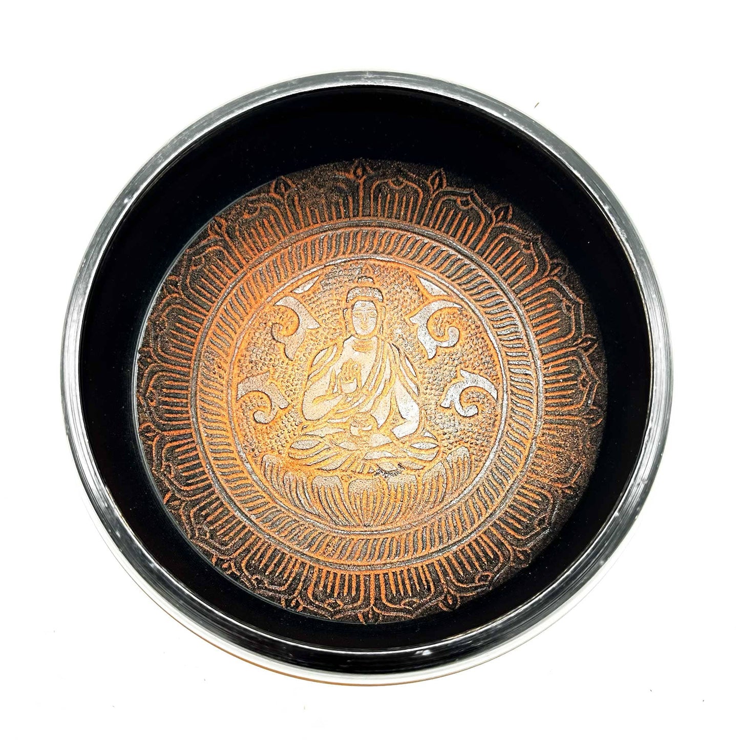 Intérieur d'un bol tibétain orange avec un Bouddha gravé au centre.