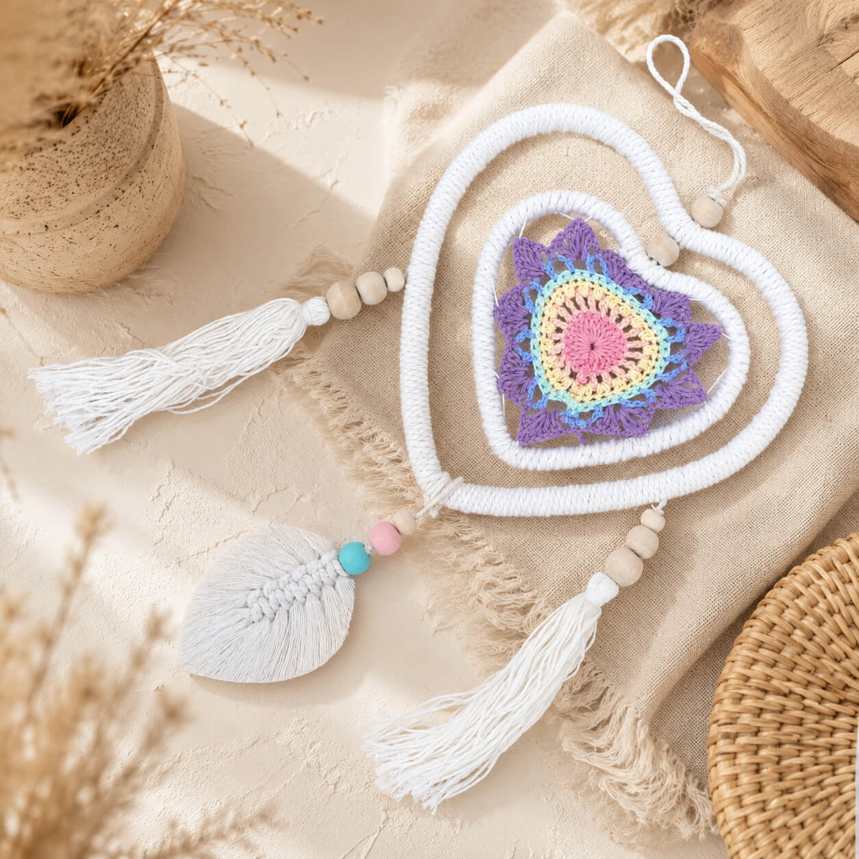 Détail du mandala crocheté pastel au centre du double cœur avec feuille macramé et perles colorées.