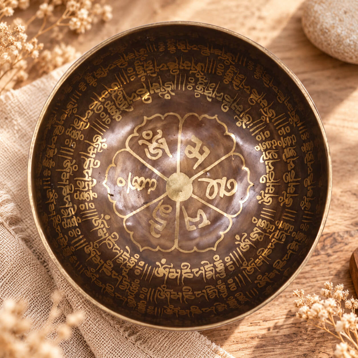 Intérieur gravé du bol chantant, avec une fleur à six pétales portant chacune une syllabe du mantra