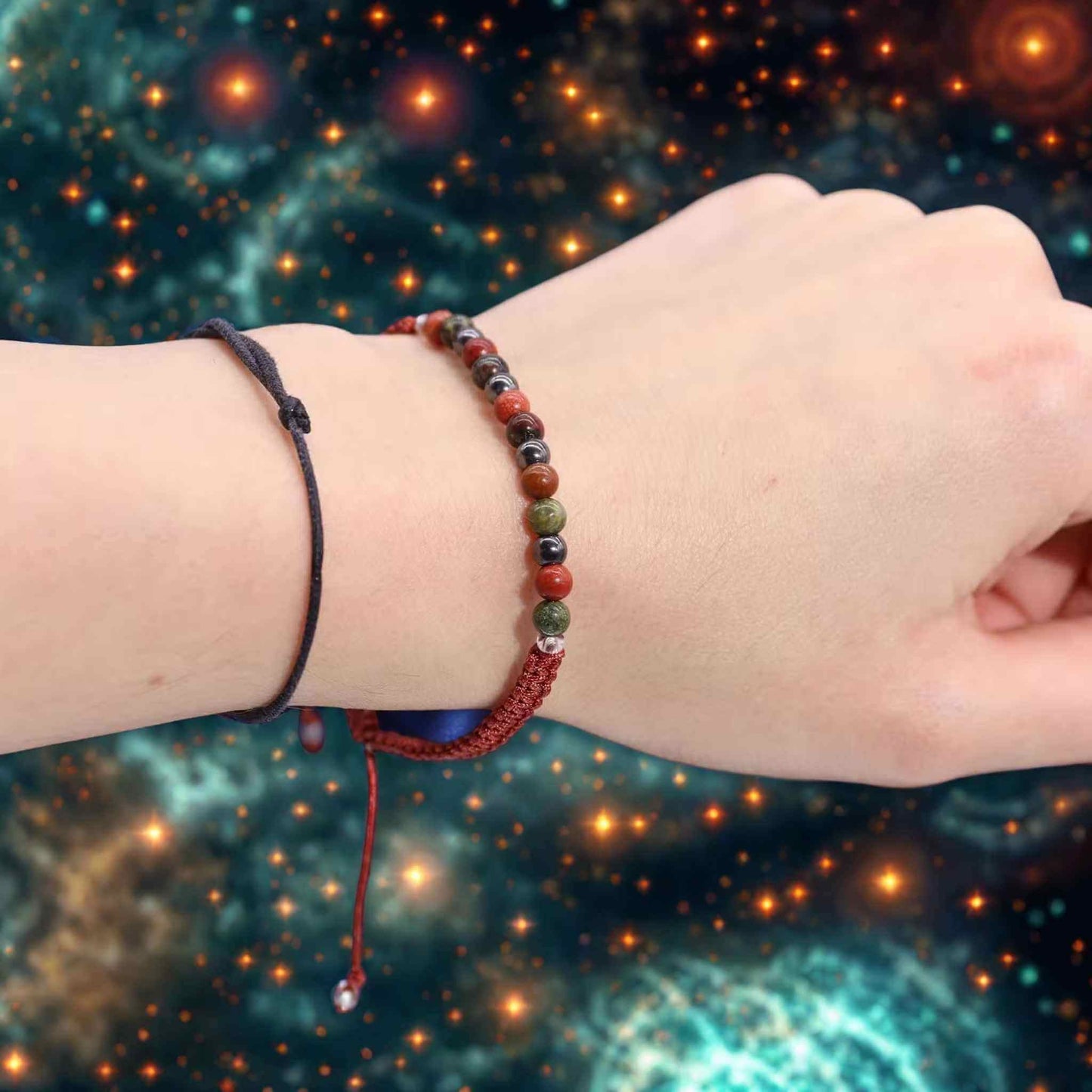 Bracelet astrologique Bélier en jaspe rouge, bloodstone et hématite porté au poignet sur fond étoilé.