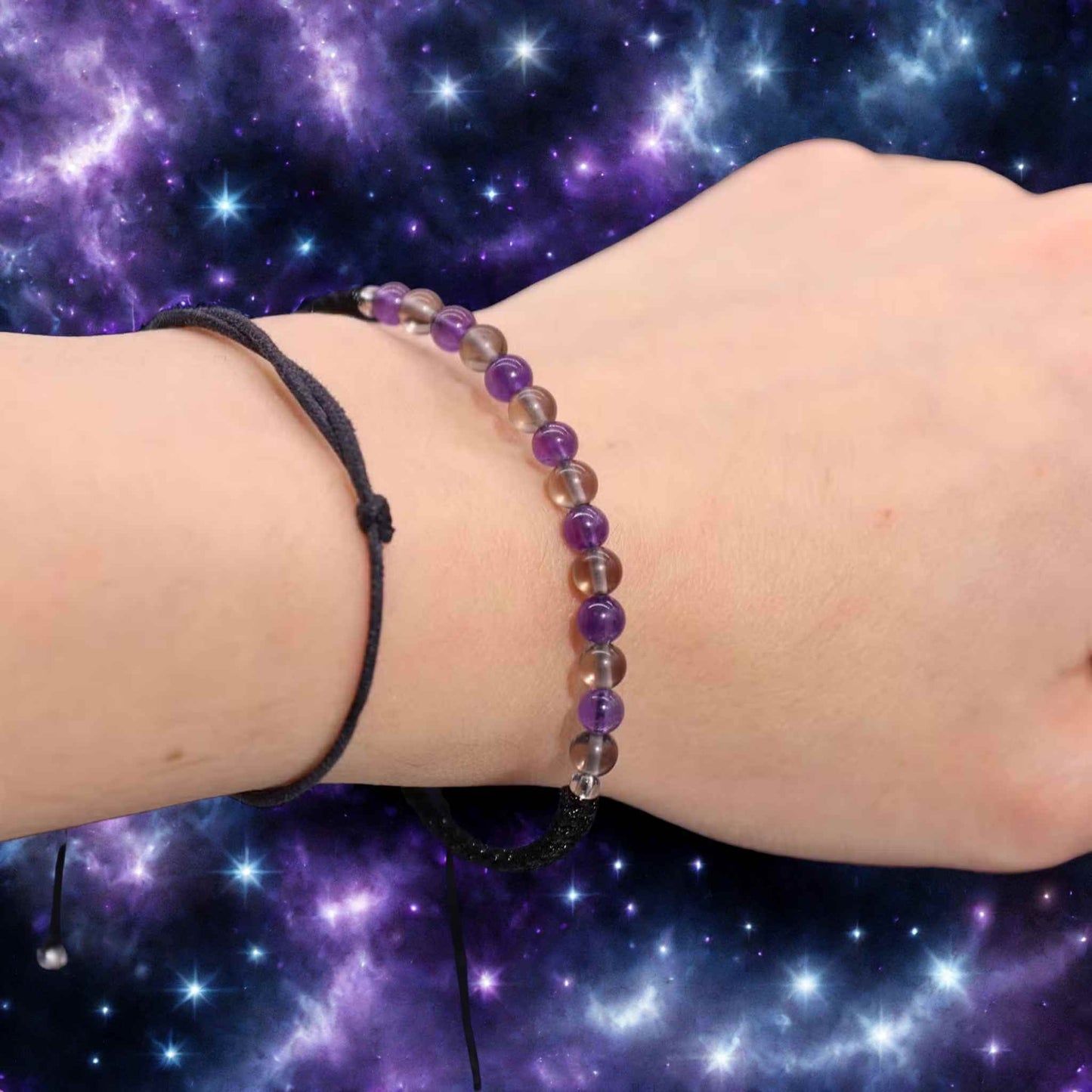 Bracelet astrologique Capricorne en améthyste et quartz fumé porté au poignet sur fond étoilé.