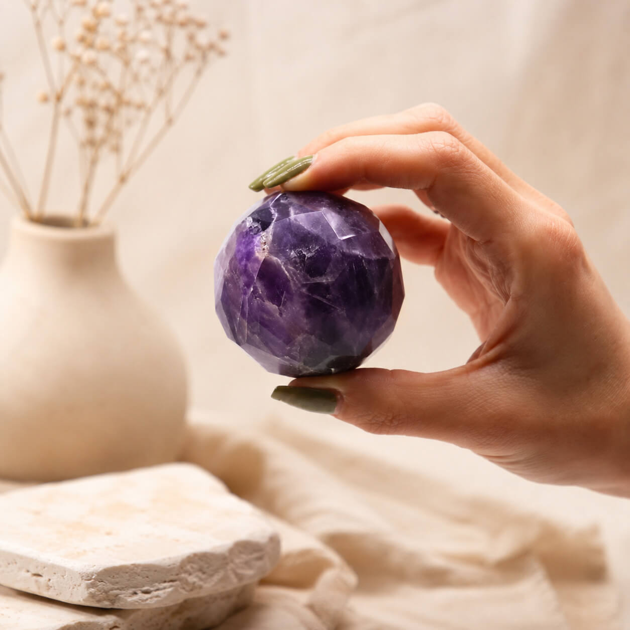 Boule d'améthyste violette à facettes tenue entre les doigts