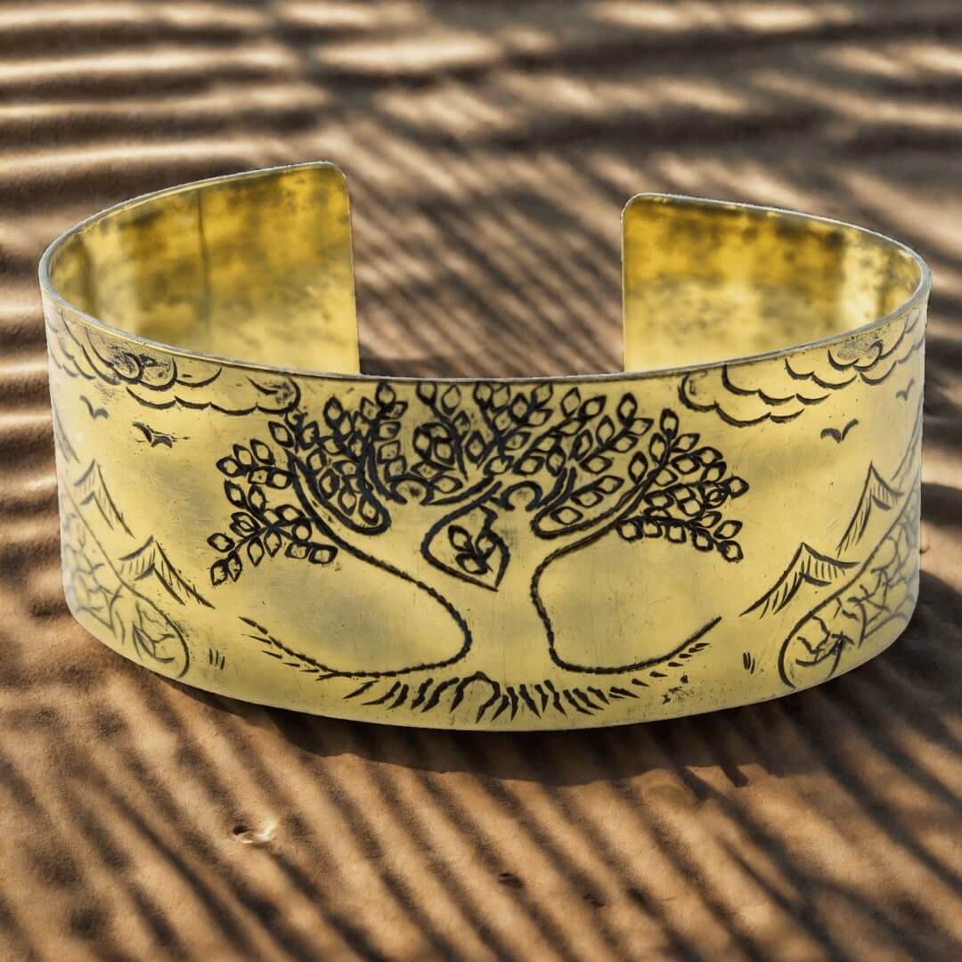 Bracelet tibétain en laiton avec arbre de vie gravé, photographié sur sable strié avec jeux d'ombres naturelles.