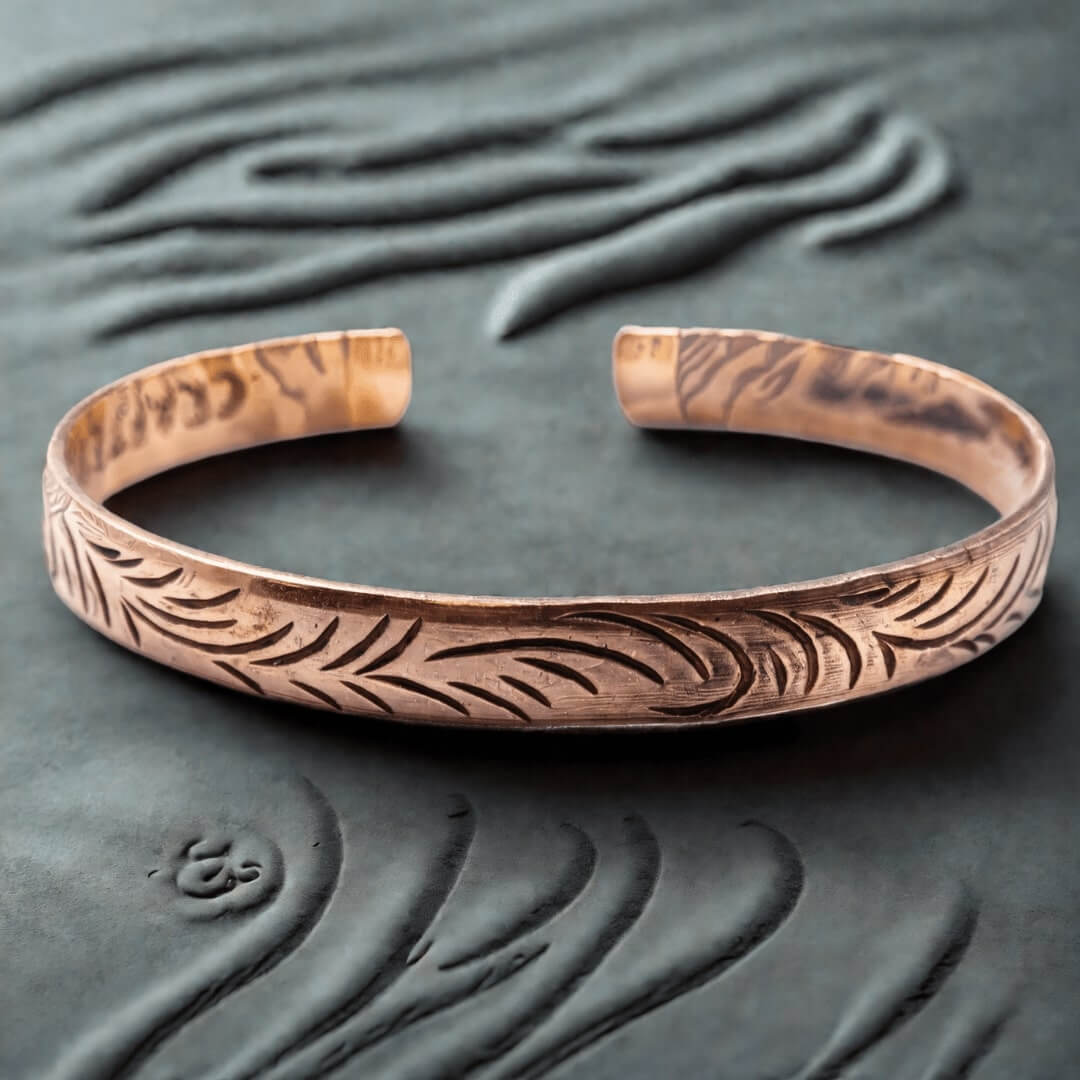 Bracelet tibétain manchette fine en cuivre avec gravures de feuilles sur fond texturé.