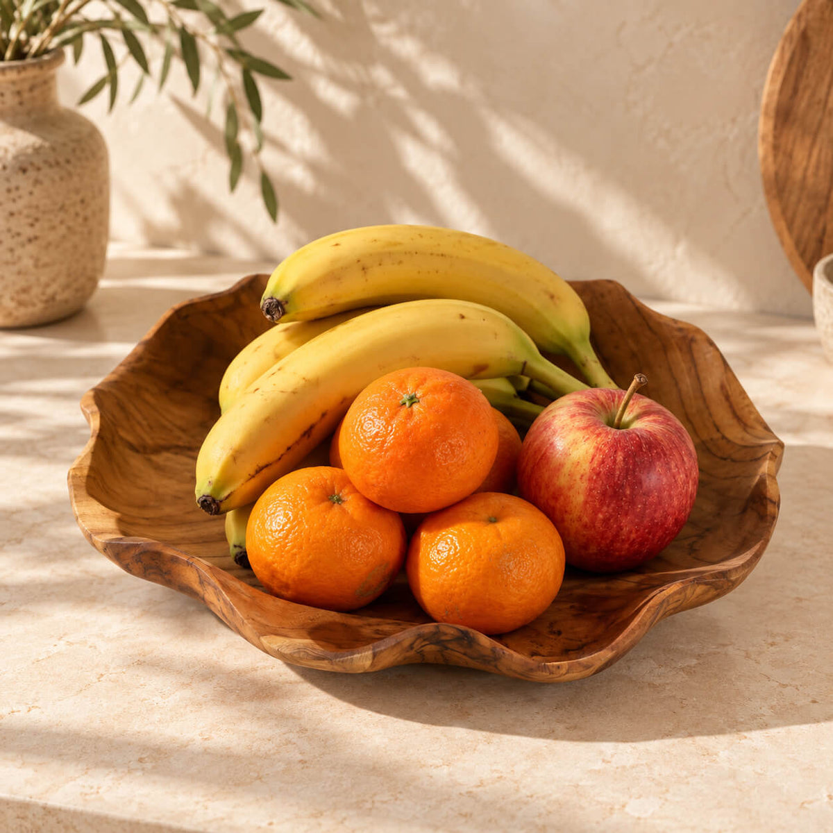 Coupe en teck ronde garnie de bananes, oranges et une pomme