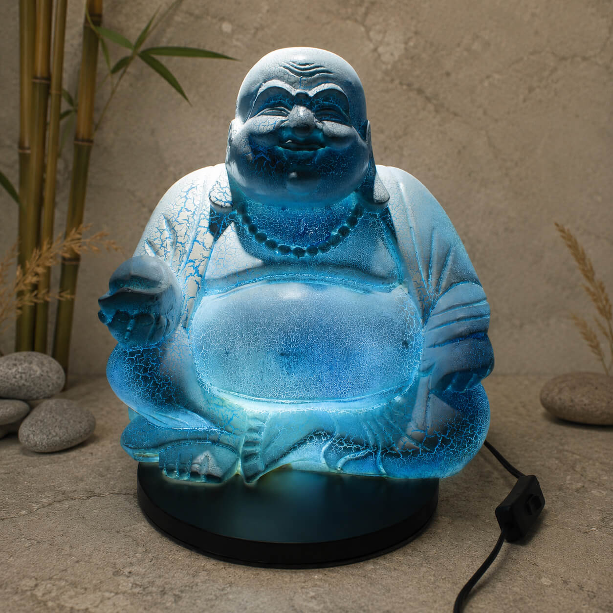 Lampe Bouddha rieur bleu ciel craquelée allumée diffusant une lumière bleutée dans un coin détente.