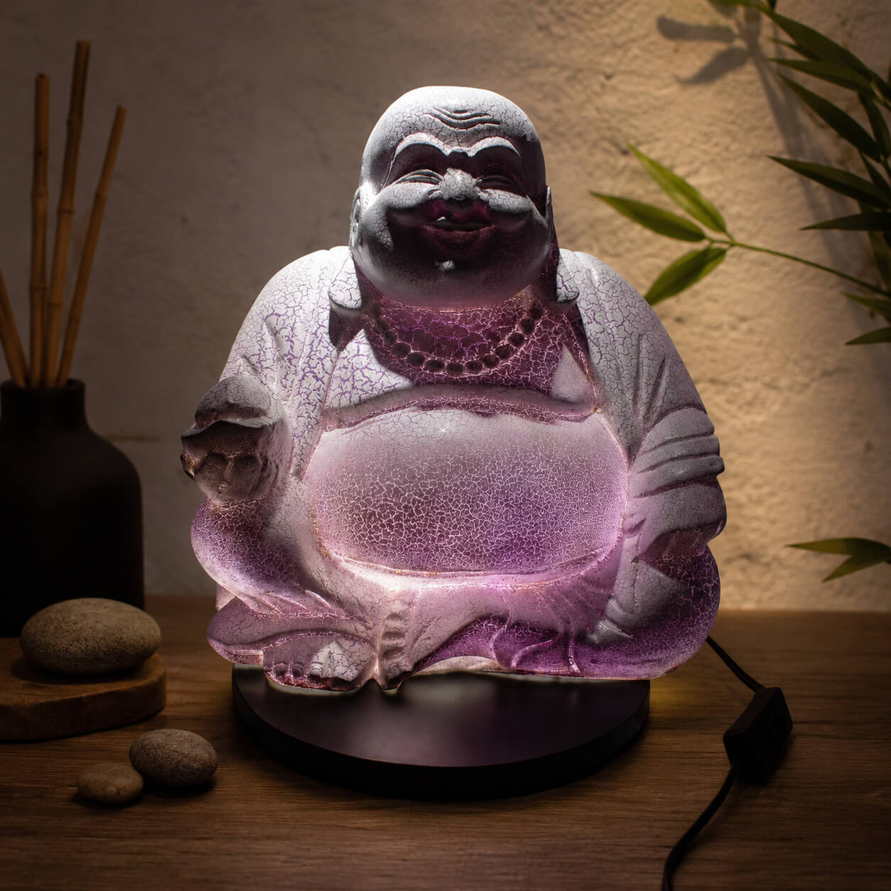 Lampe Bouddha rieur lavande craquelée allumée diffusant une lumière violacée dans un coin détente.