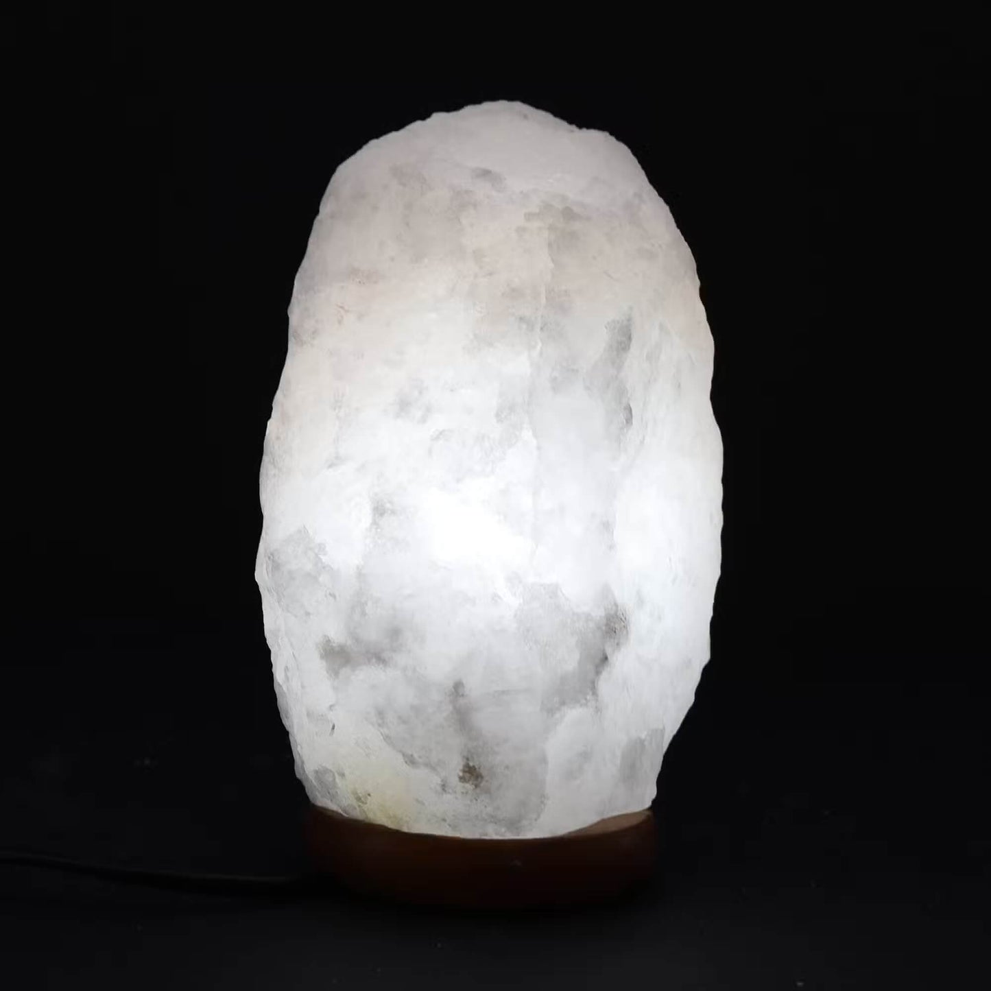 Lampe en cristal de roche blanc allumée diffusant une lumière douce et translucide à travers le quartz.