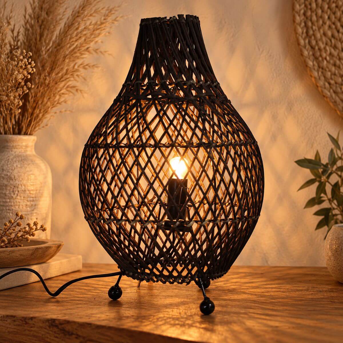 Lampe en rotin noir allumée, projetant des ombres en losanges sur le mur