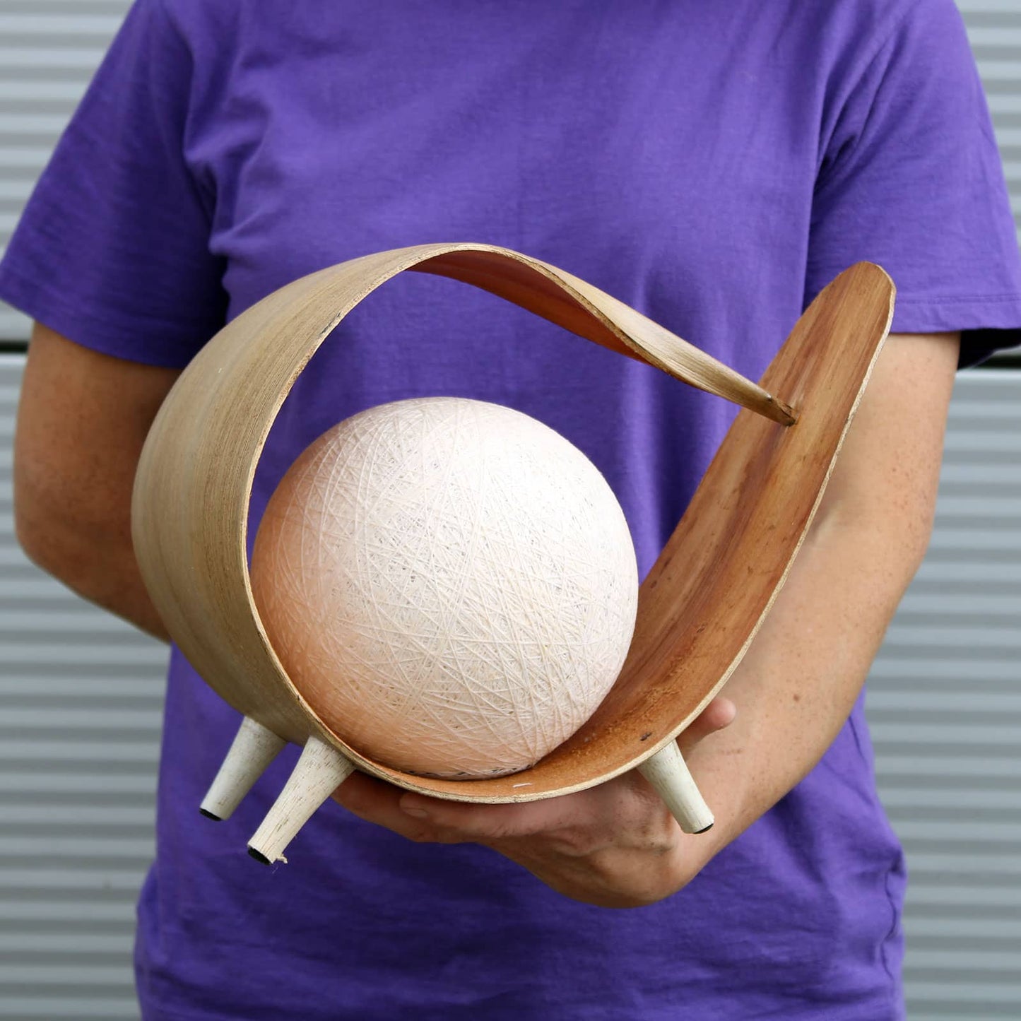 Belle lampe en feuille de coco en forme de boucle dans mains pour voir la taille.