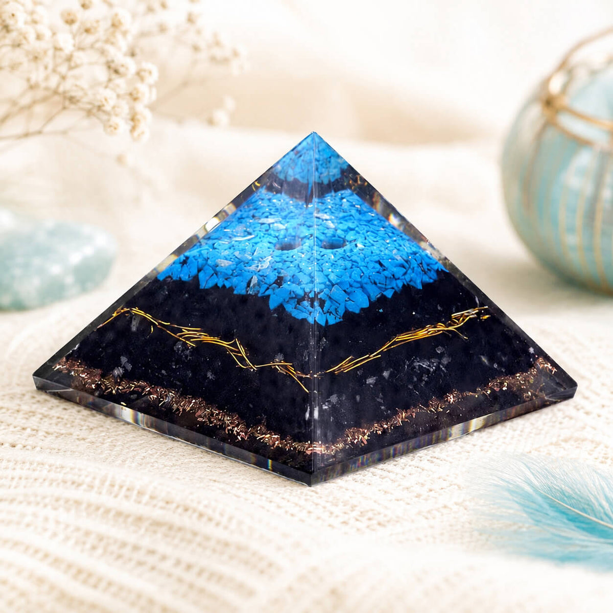 Pyramide en orgonite montrant les fils de cuivre doré traversant la base sombre