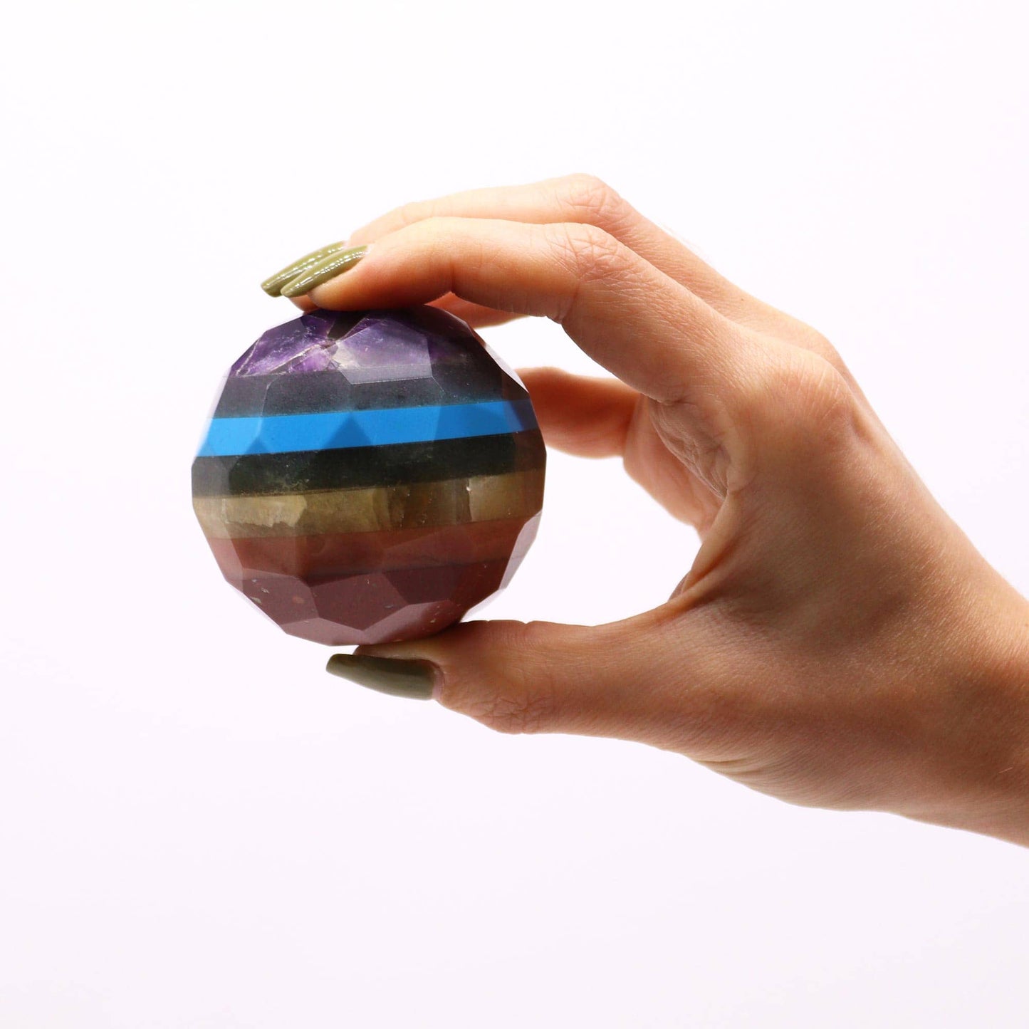 Sphère multicolore des 7 chakras sur dans main, reflets harmonieux des différentes pierres naturelles.