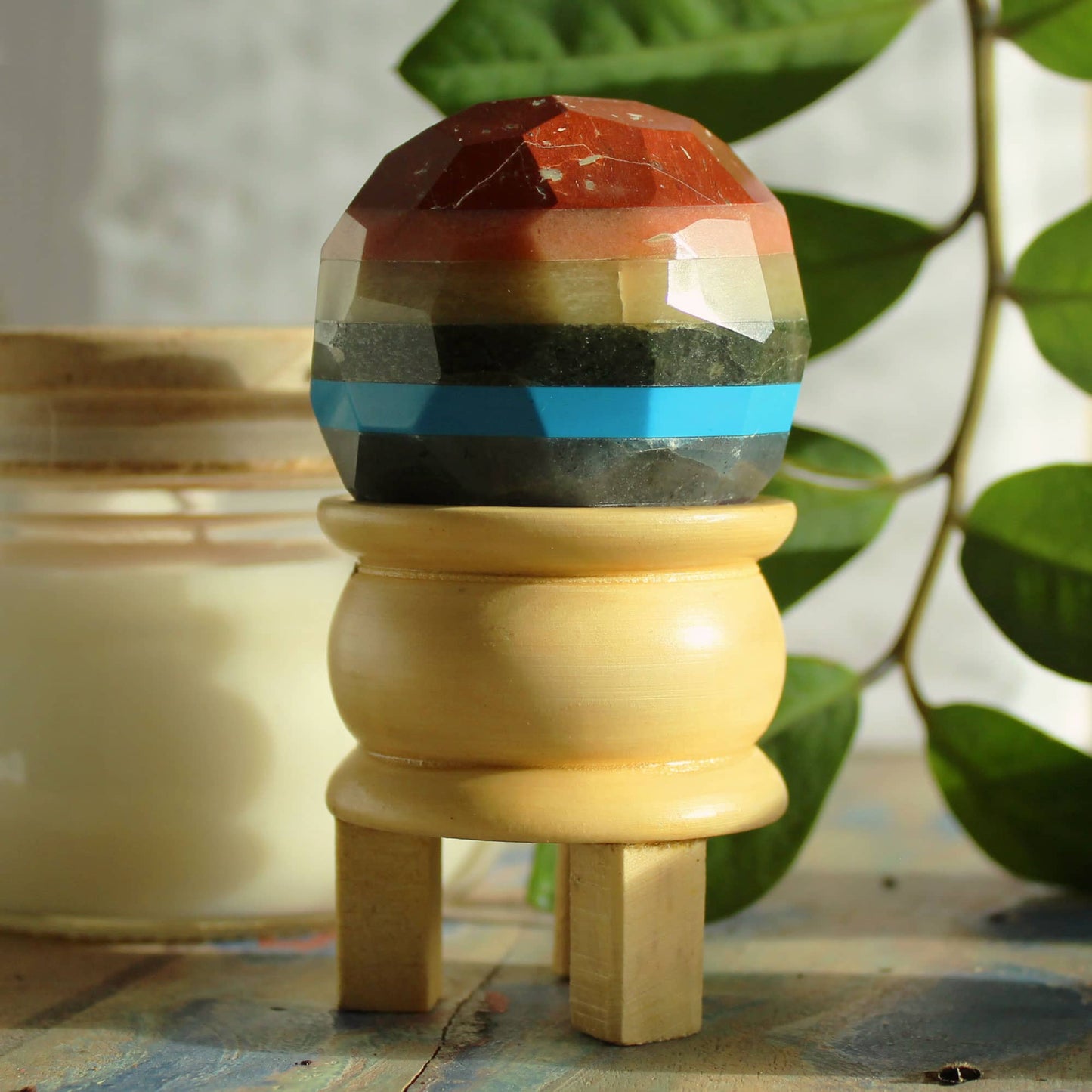 Sphère multicolore des 7 chakras sur élégant support en bois, reflets harmonieux des différentes pierres naturelles