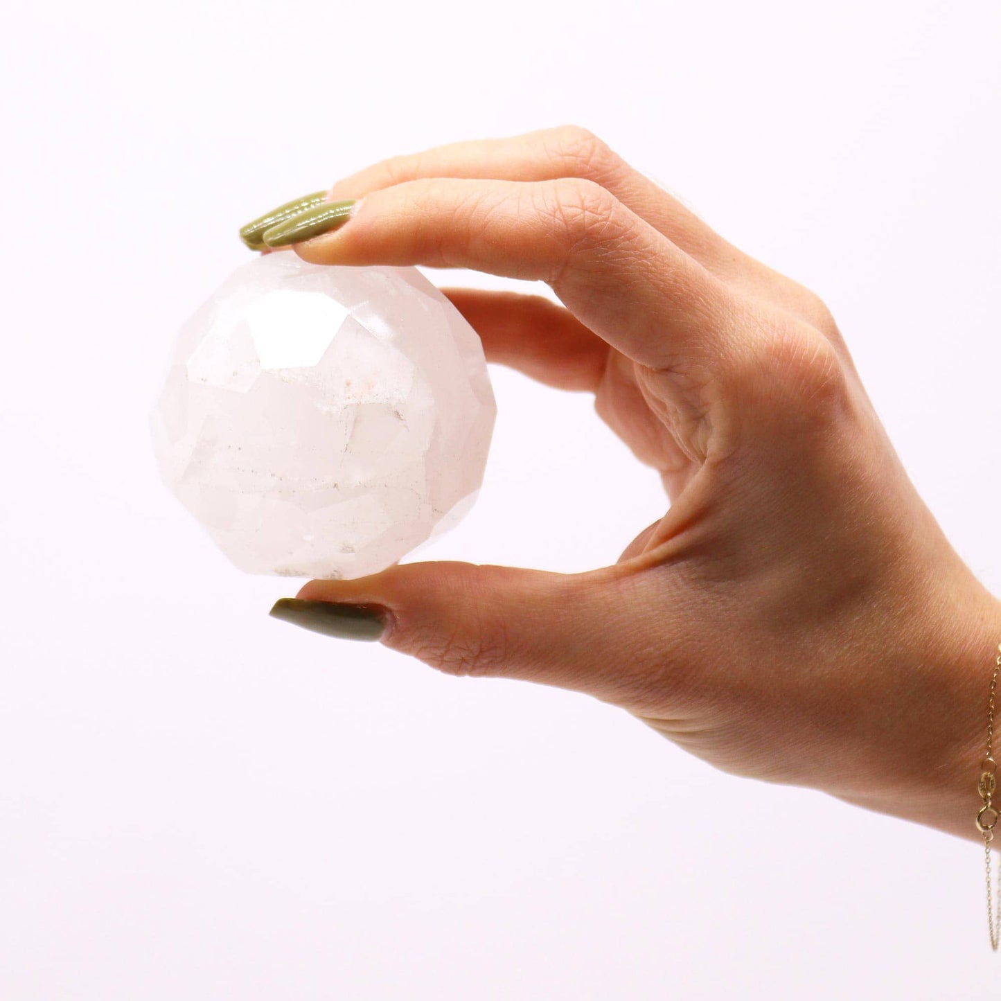 Sphère facettée en Quartz Blanc cristallin aux reflets purs et lumineux dans une main.