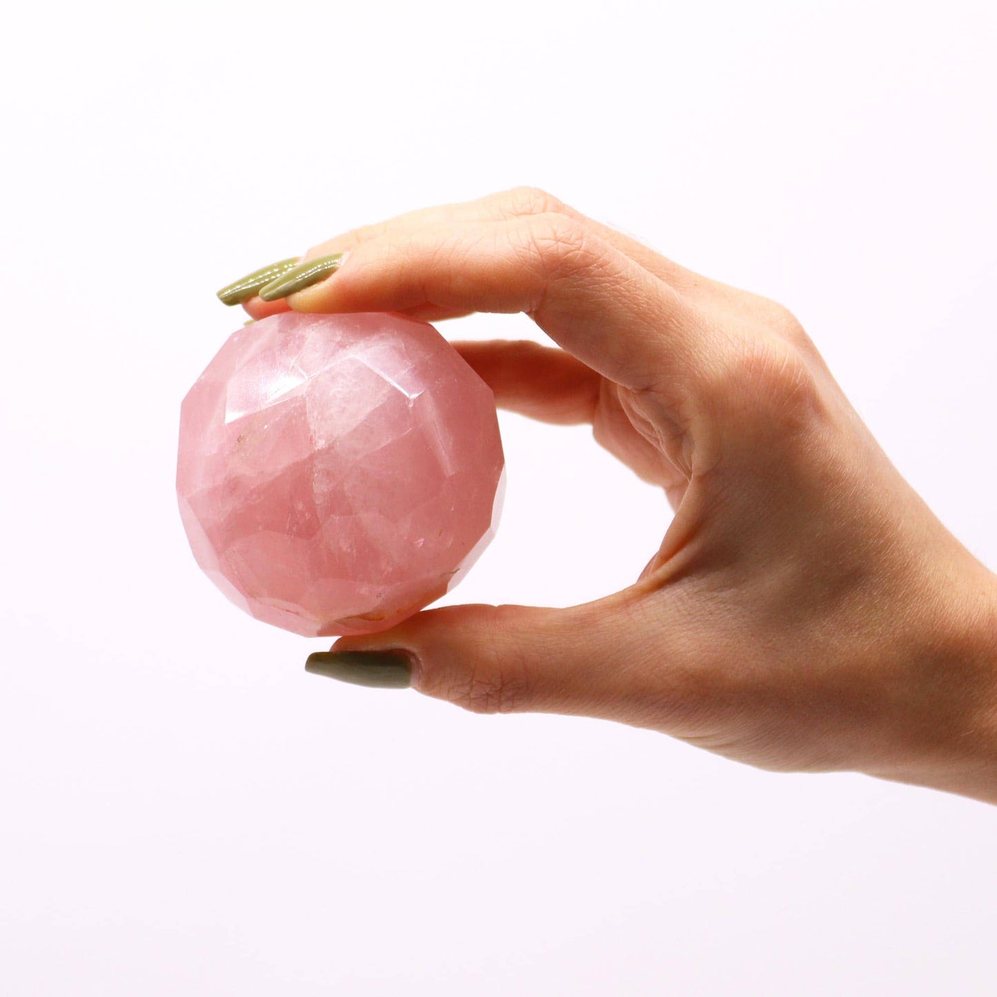 Sphère facettée en Quartz Rose aux reflets doux et rosés dans main.