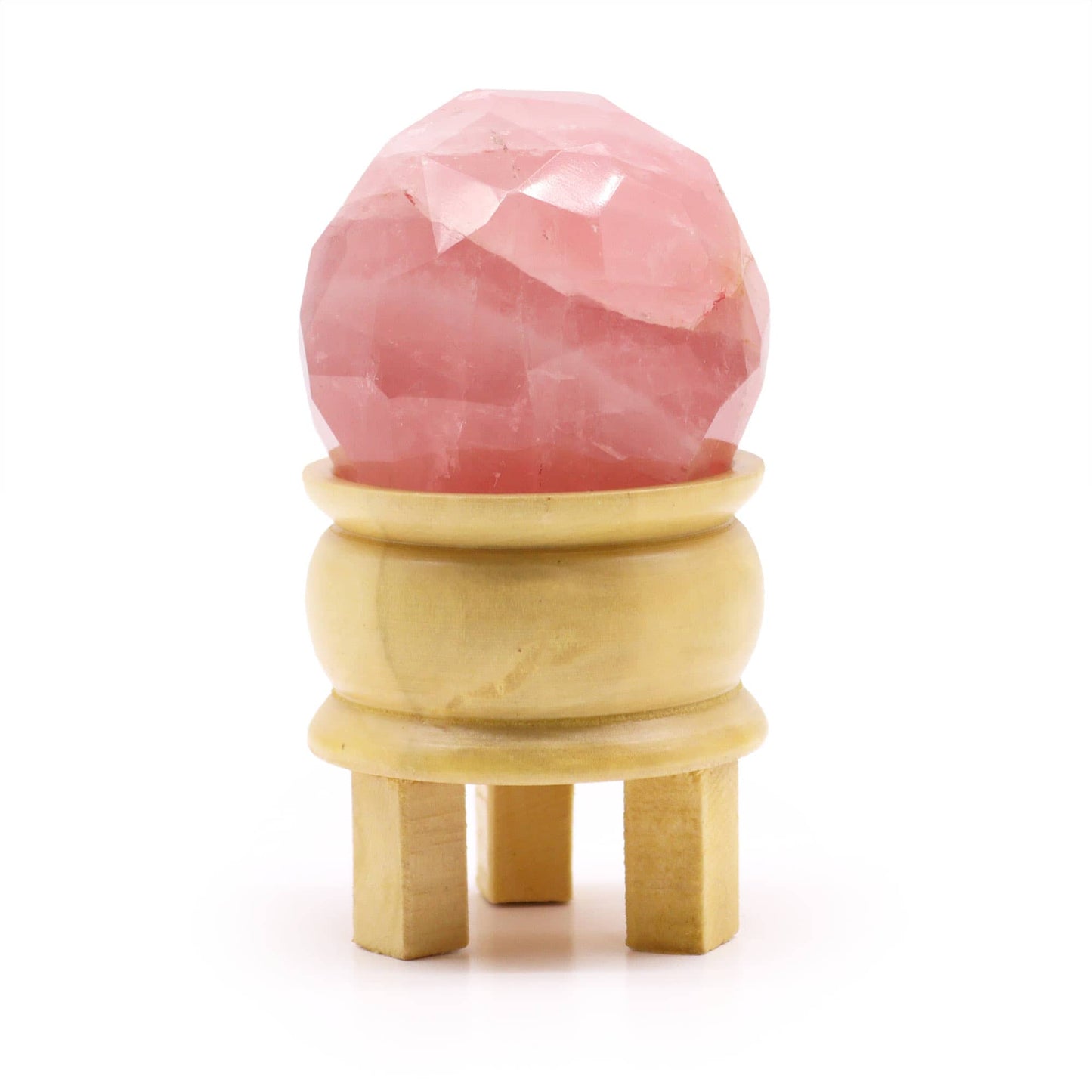Sphère facettée en Quartz Rose aux reflets doux et rosés, montée sur un support en bois clair sur fond blanc.