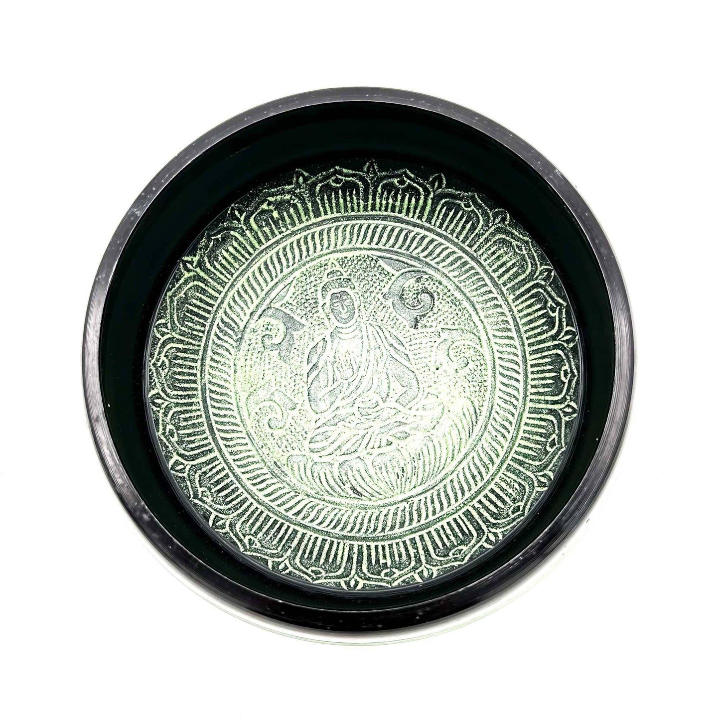 Intérieur d'un bol tibétain vert et noir avec un Bouddha gravé au centre.