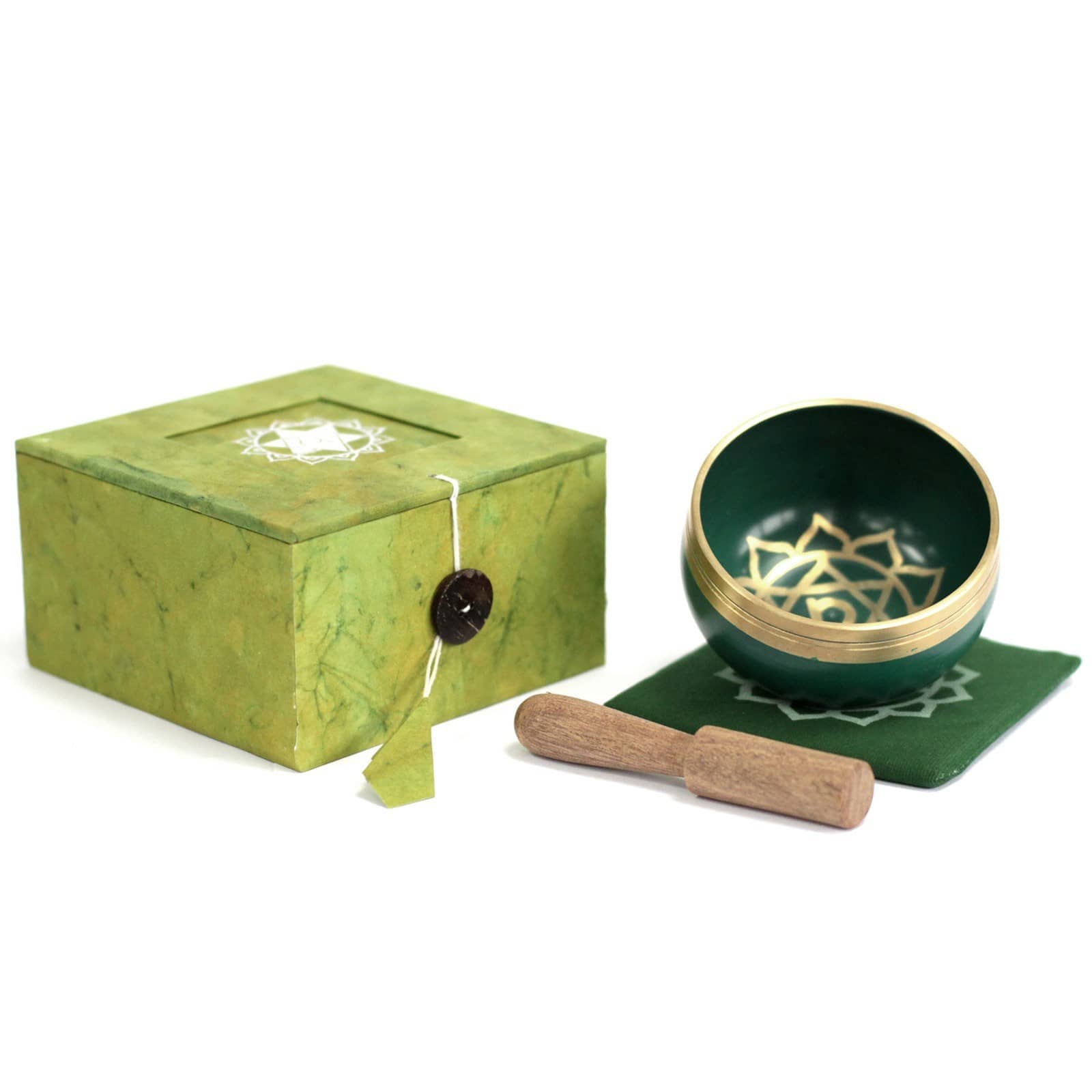 Coffret ouvert vert contenant un bol tibétain vert avec une bordure dorée. À l'intérieur, le symbole du Chakra Cœur doré, posé sur un tapis vert, accompagné d'un fuseau en bois.