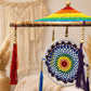 Vue rapprochée du parasol crocheté arc-en-ciel sur structure en bambou avec perles et pompons.