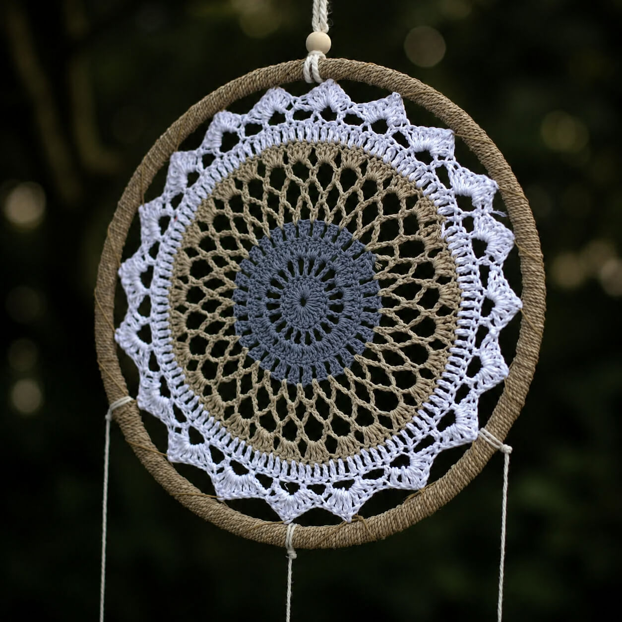Détail du médaillon crocheté en mandala blanc et gris bleuté sur cerceau enroulé de jute naturel.