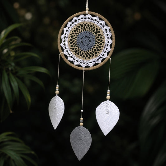 Attrape-rêve rond avec mandala crocheté blanc beige et gris bleuté et trois plumes tissées en forme de feuilles.