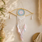 Attrape-rêve en forme d'œil avec médaillon crocheté bleu et rose pastel, macramé écru et plumes naturelles suspendues.