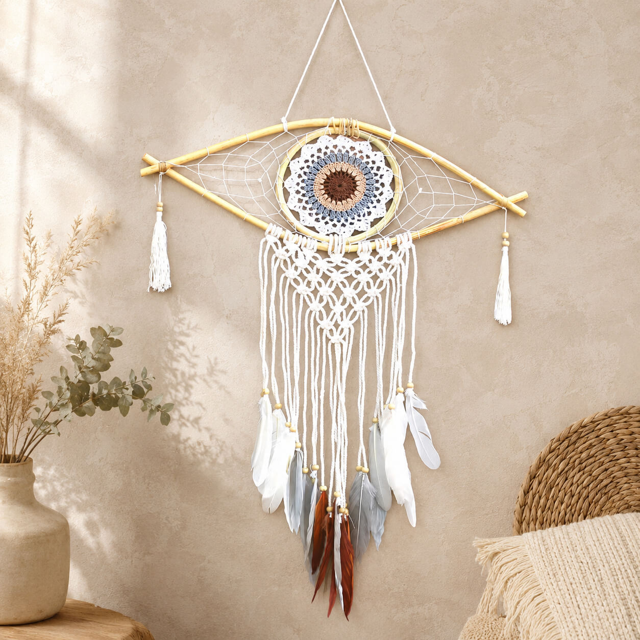 Attrape-rêve en forme d'œil avec mandala crocheté blanc bleu et marron, macramé écru et plumes terre suspendues.