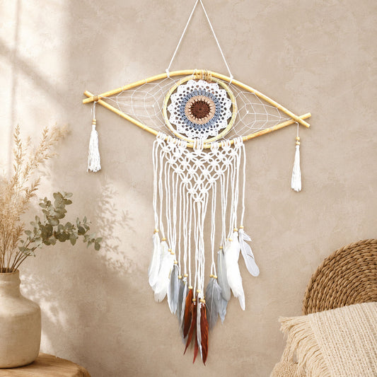 Attrape-rêve en forme d'œil avec mandala crocheté blanc bleu et marron, macramé écru et plumes terre suspendues.