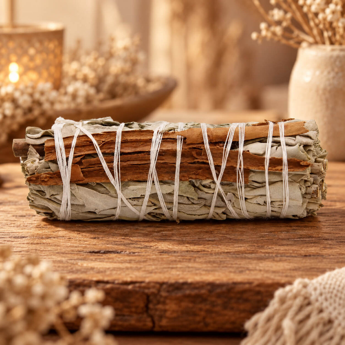 Bâton de sauge blanche avec des lamelles d'écorce de cannelle, lié par une ficelle blanche, posé sur une planche en bois
