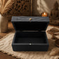Boîte à bijoux noire ouverte, intérieur laqué noir et fermeture à charnières.