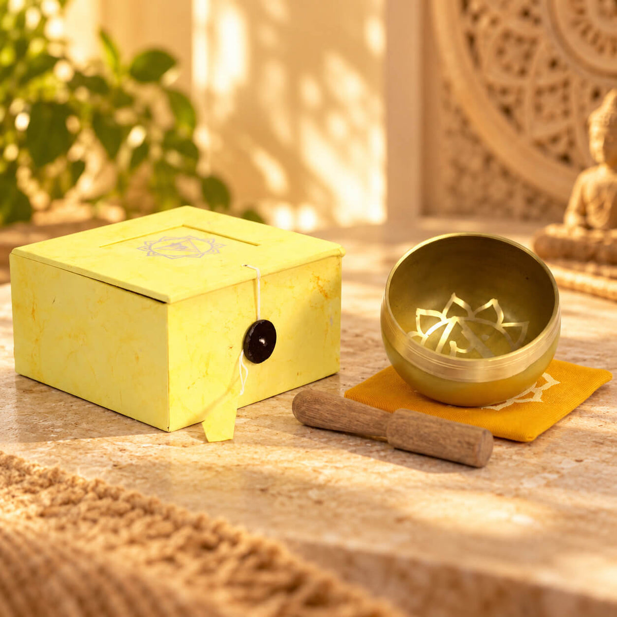 Bol chantant en laiton du chakra plexus solaire sur son coussin moutarde, à côté de sa boîte jaune et de son bâton