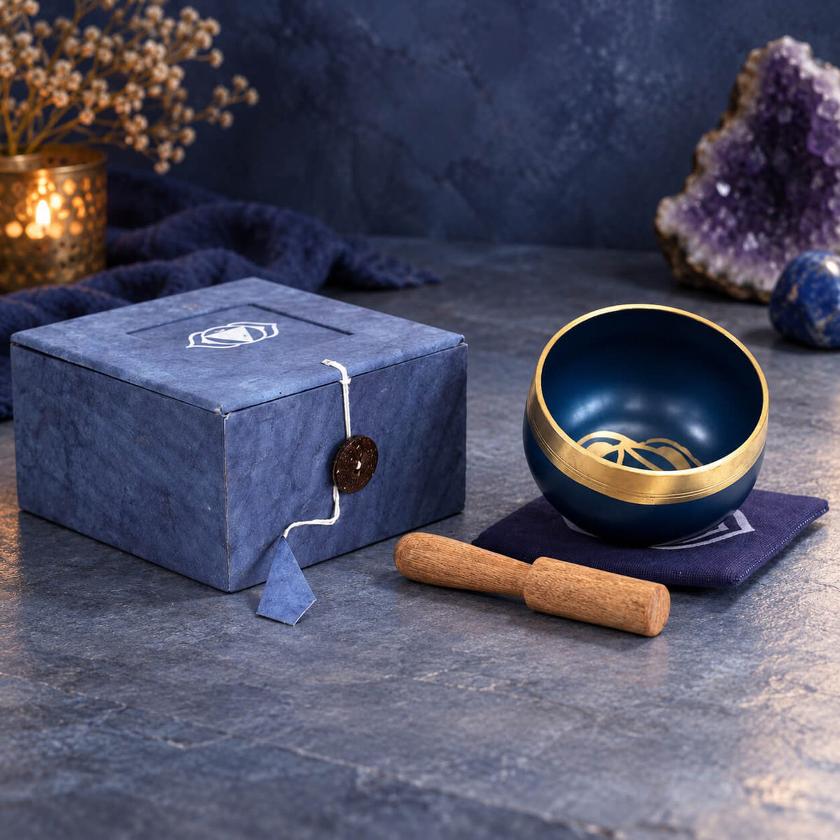 Bol chantant bleu roi et or du troisième œil sur son coussin bleu marine, à côté de sa boîte bleue fermée