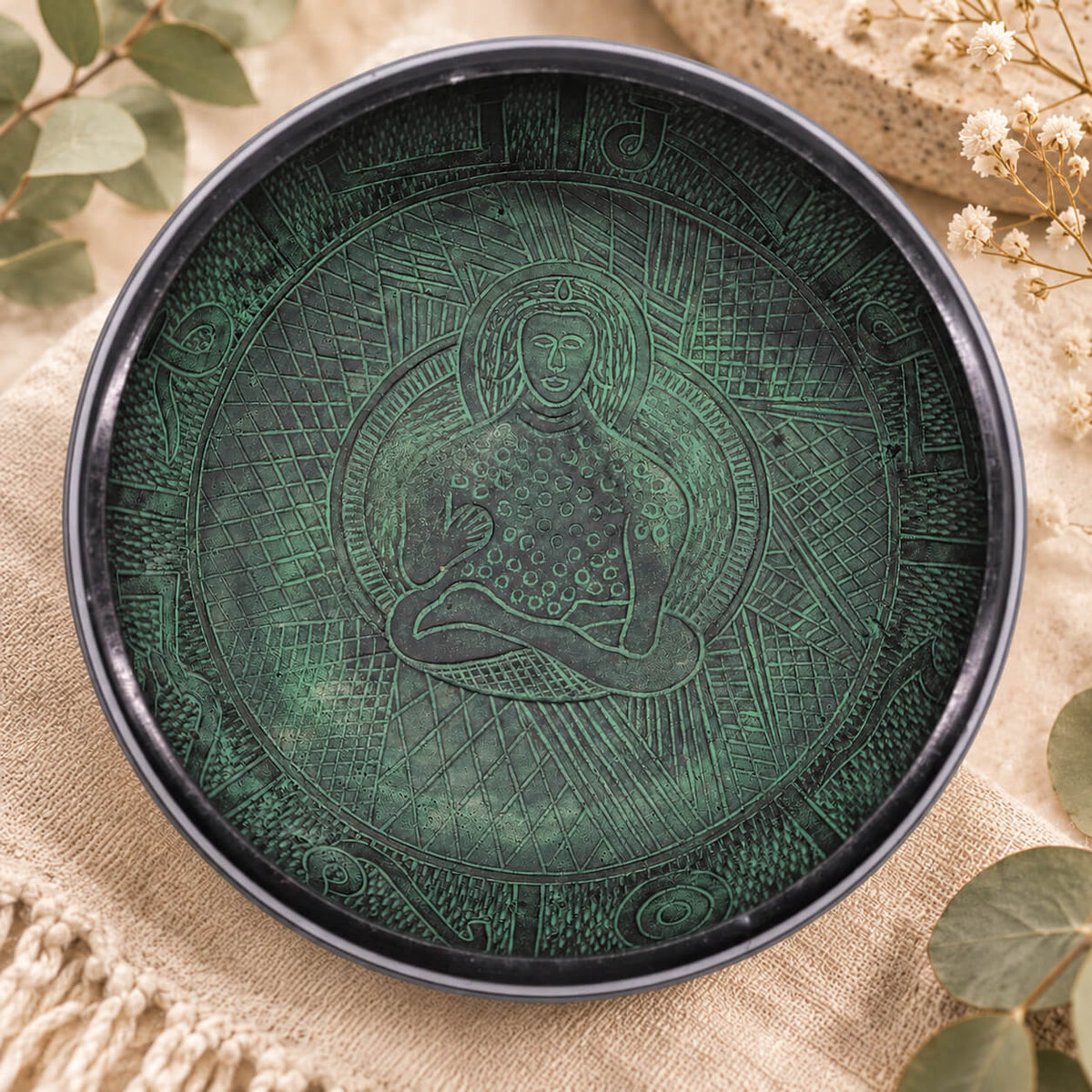 Intérieur vert du bol chantant gravé d’un Bouddha en méditation, entouré de hachures et de lettres stylisées