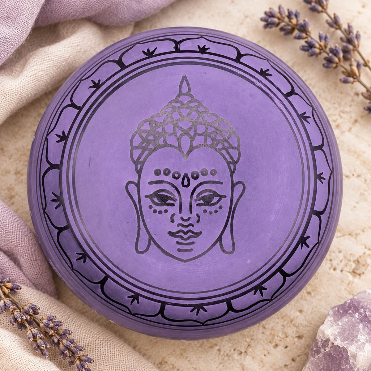 Dessous du bol chantant violet gravé d’un visage de Bouddha dans une couronne de pétales de lotus