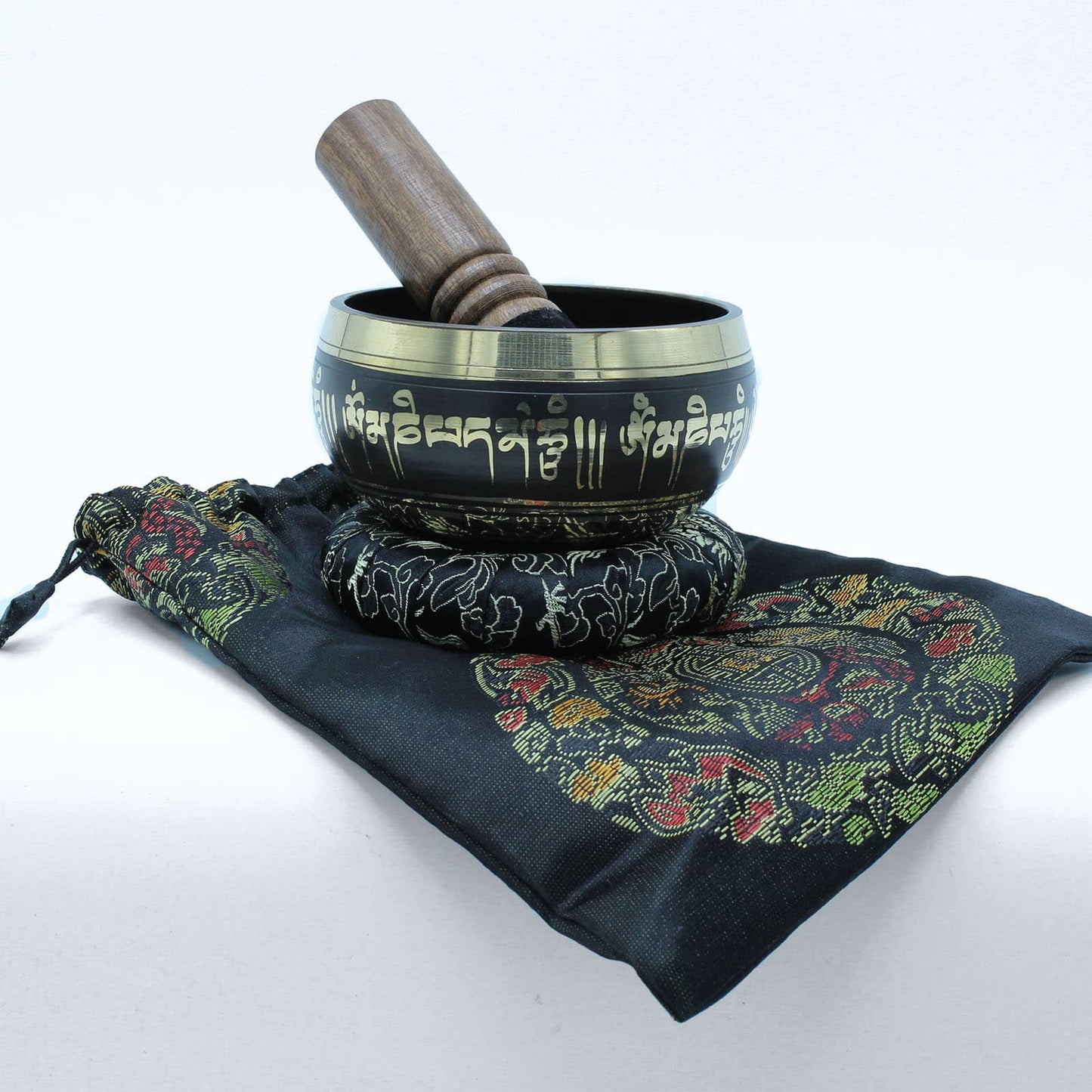 Un bol tibétain noir avec des bordures dorées et des mantras dorés gravés, posé sur un coussin qui est lui-même placé sur un sac assorti.