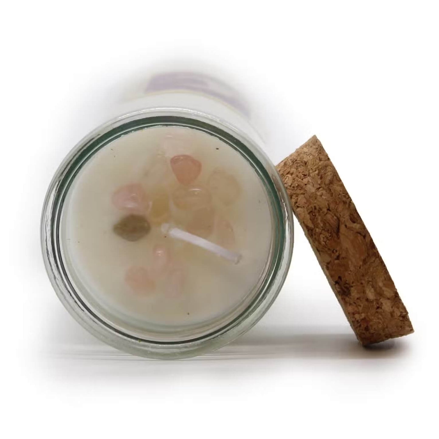 Vue plongeante d’une bougie rituel amour en verre montrant des éclats de quartz rose autour de la mèche avec bouchon de liège à côté prête pour un rituel d’amour et de connexion
