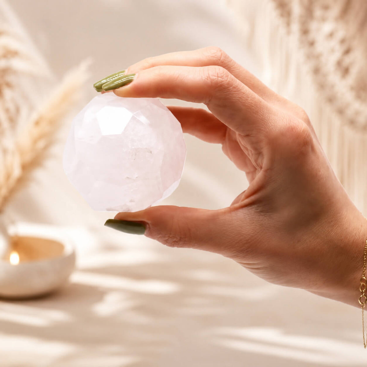 Boule de cristal de roche à facettes tenue entre les doigts