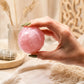 Boule de quartz rose à facettes tenue entre les doigts