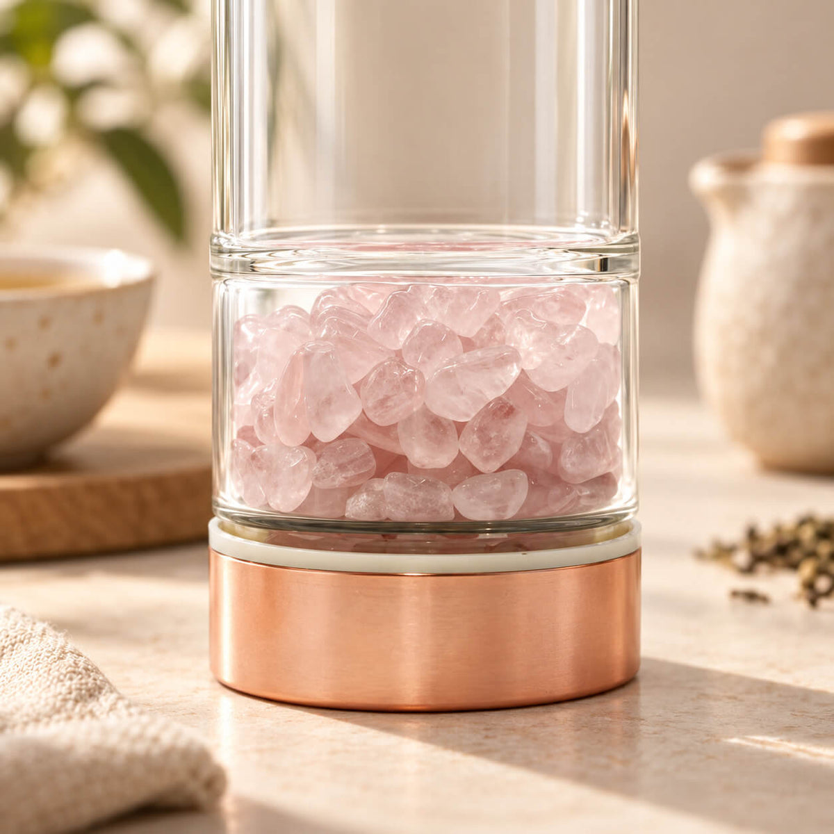 Détail du compartiment à éclats de quartz rose au pied de la bouteille à thé en verre