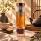 Bouteille à thé en verre avec finition or rose, infuseur inox et thé infusé bien visible