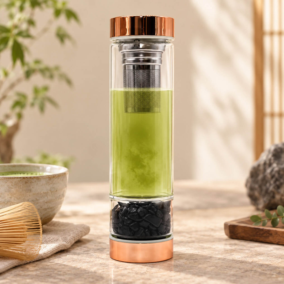 Bouteille à thé en verre avec thé vert infusé et éclats d'onyx noir à la base