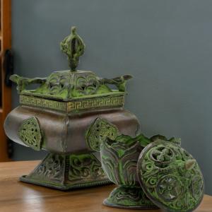 Collection de brûleurs d'encens verdigris, modèle urne et lotus, photographiés dans une ambiance zen.