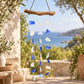 Carillon à vent en éclats de verre recyclé bleu et blanc suspendus à une simple branche de bois flotté