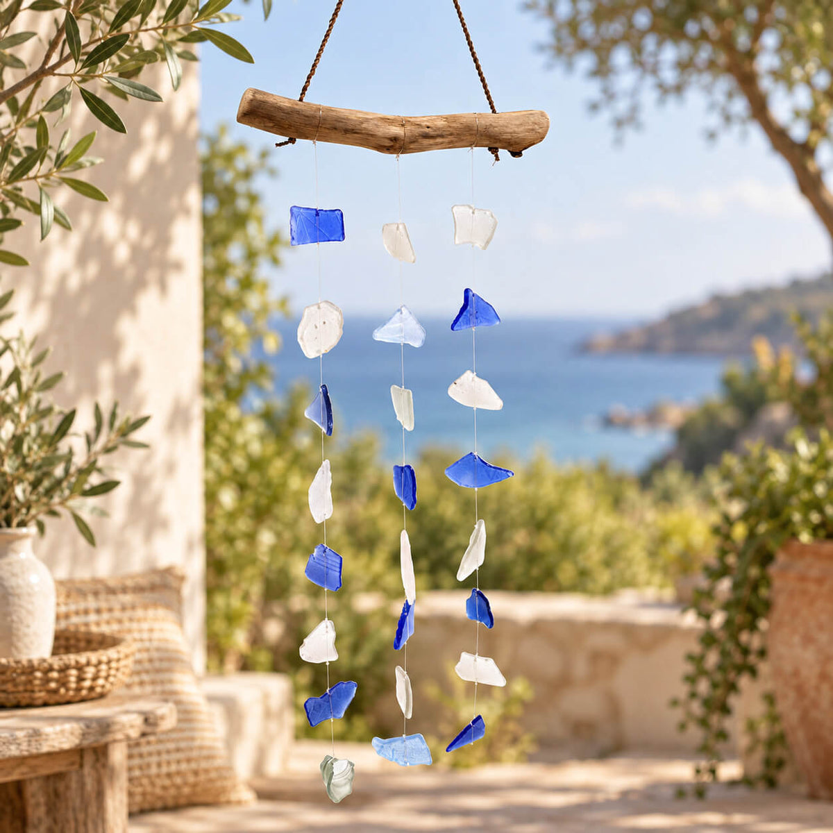 Carillon à vent en éclats de verre recyclé bleu et blanc suspendus à une simple branche de bois flotté