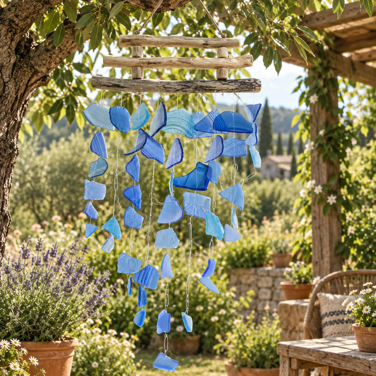 Vue rapprochée du carillon en verre bleu recyclé, dégradé du bleu pâle au bleu marine, suspendu sous un arbre