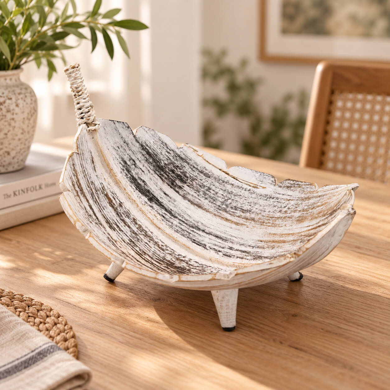 Coupe à fruits en feuille de coco à la finition blanchie, posée sur une table en bois