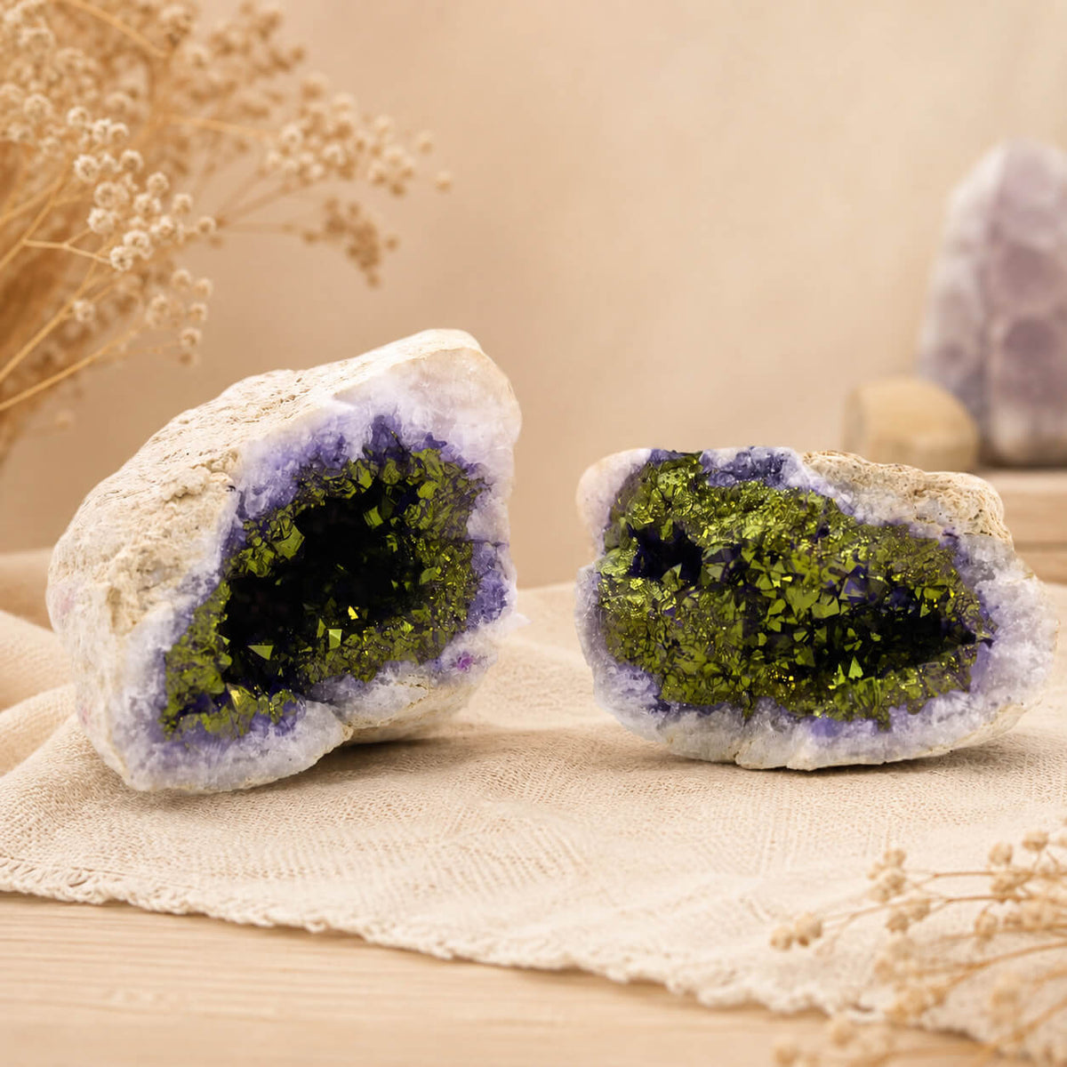 Deux géodes de calcite colorée violet et or ouvertes révélant leurs cristaux scintillants.