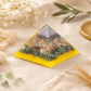 Grande pyramide orgonite chakra posée dans une ambiance naturelle avec branche d'olivier