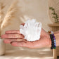 Grappe de quartz clair transparent tenue dans une main avec bracelets en pierres naturelles