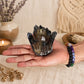 Grappe de quartz fantôme fumé tenue dans une main avec bracelets en pierres naturelles